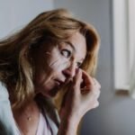 A woman applies an eye patch symbolizing self-care and relaxation indoors.