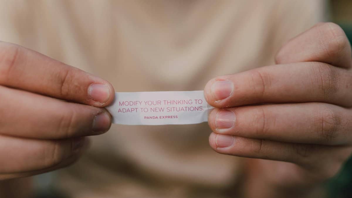 Close-up of hands holding a fortune cookie paper with insightful message