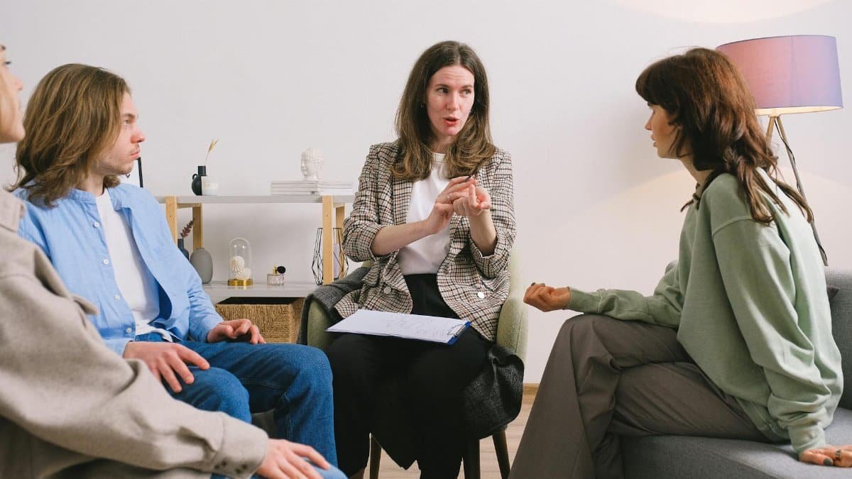 Female therapist during group session talking to female patients gathering in light cozy office