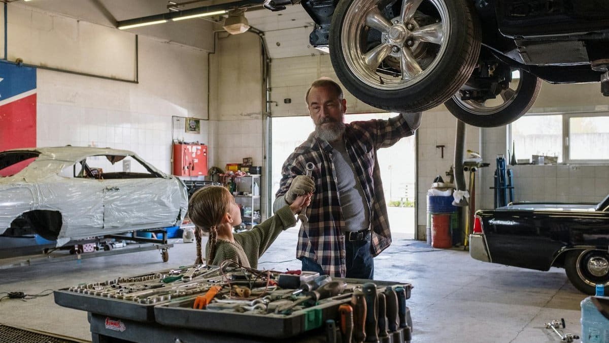 Father and daughter bonding while repairing a car in an auto workshop, symbolizing family togetherness.