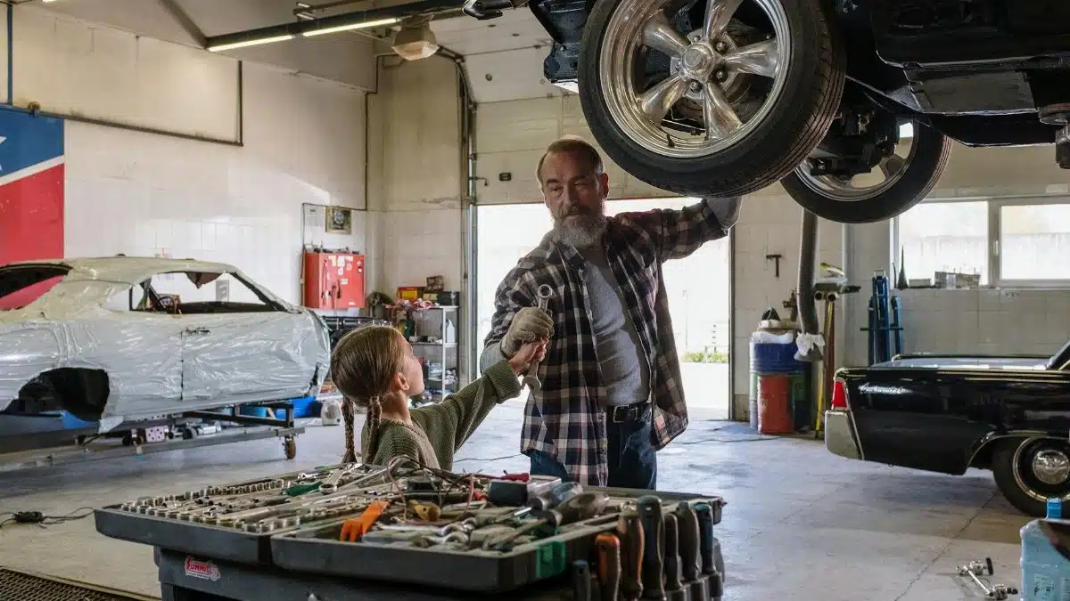 Father and daughter bonding while repairing a car in an auto workshop, symbolizing family togetherness.