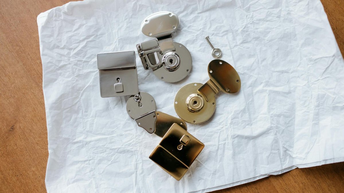 A collection of shiny metallic locks and a key displayed on crumpled paper.