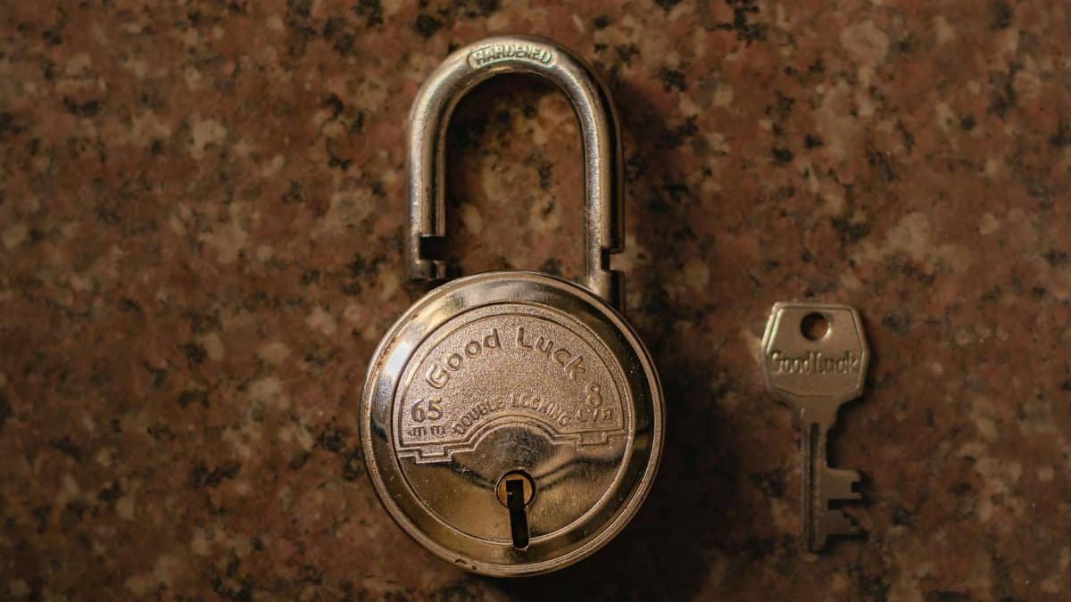 A close-up view of a vintage padlock with its key on a stone surface.