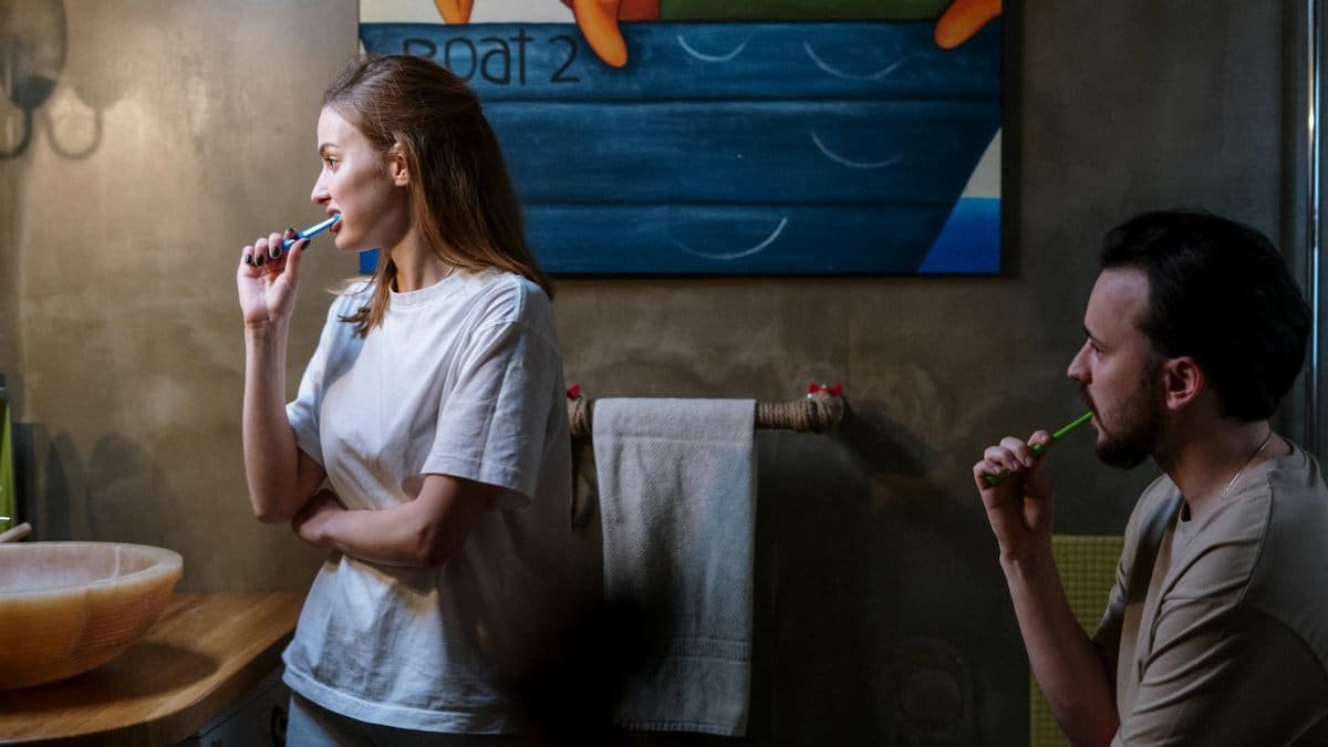 A couple brushing their teeth in a cozy bathroom during their morning routine.