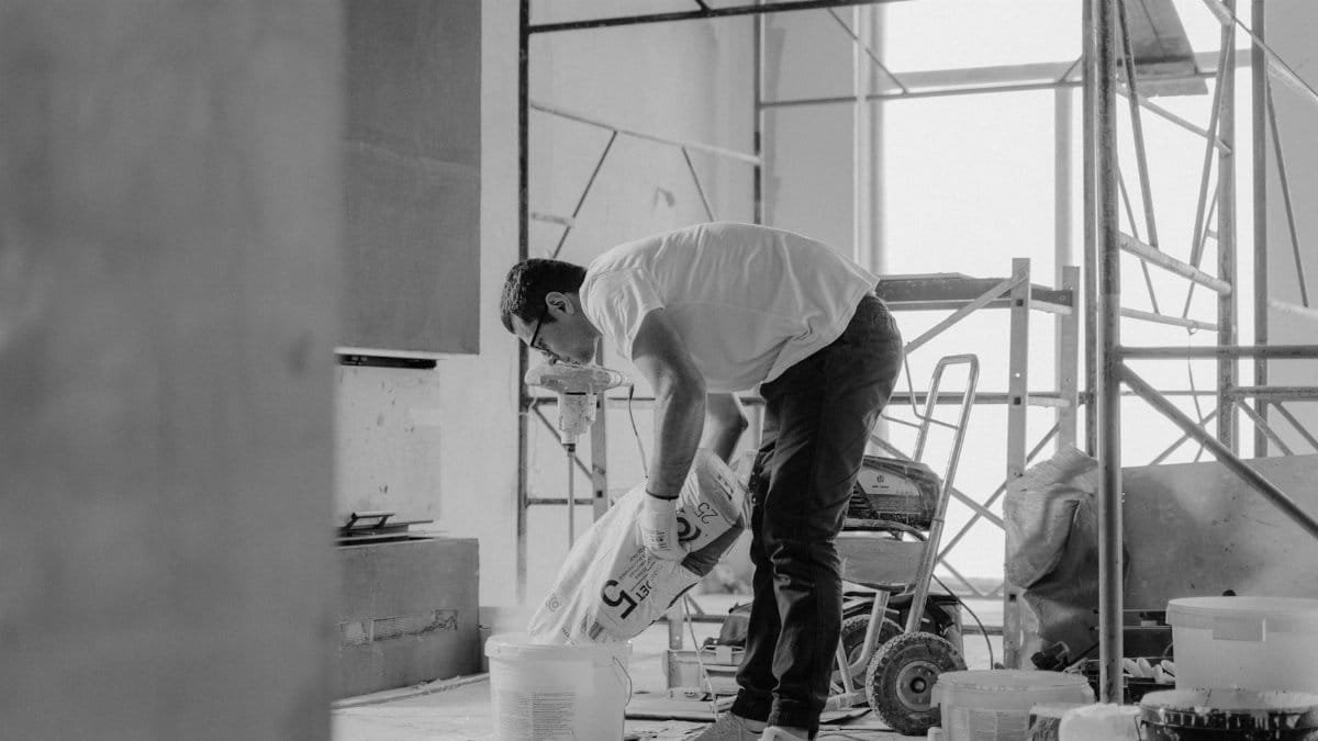 A construction worker pours materials inside a building under renovation.