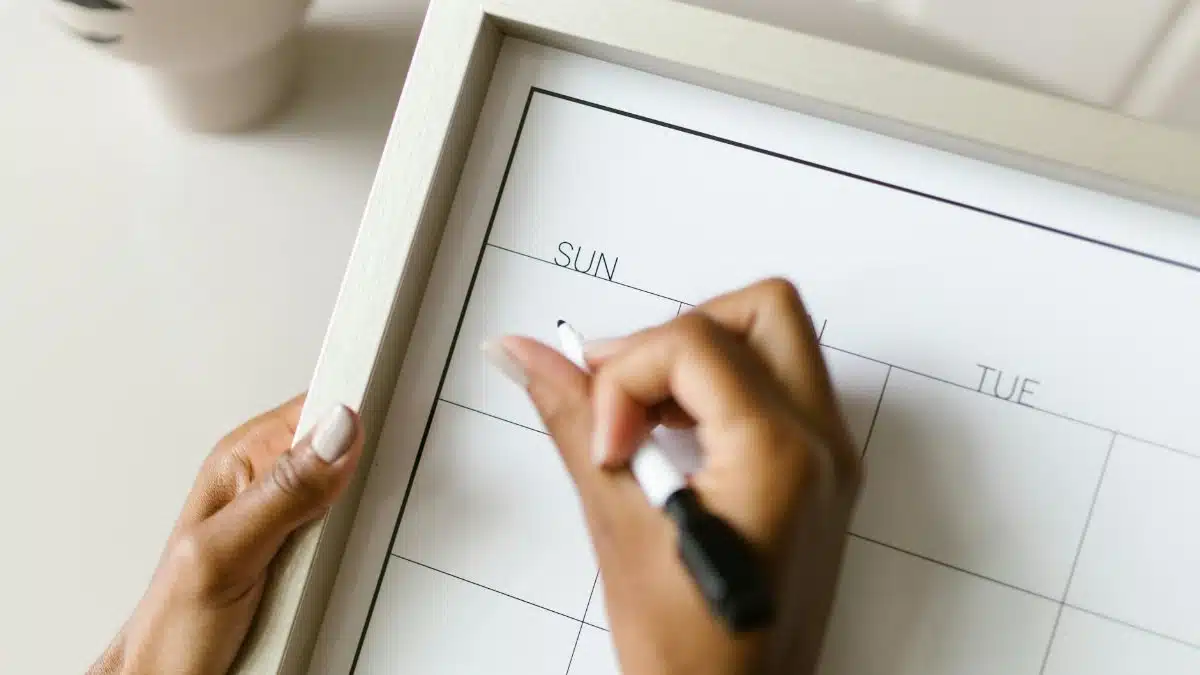 Hands holding a wall calendar, writing with a marker, organizing schedule.
