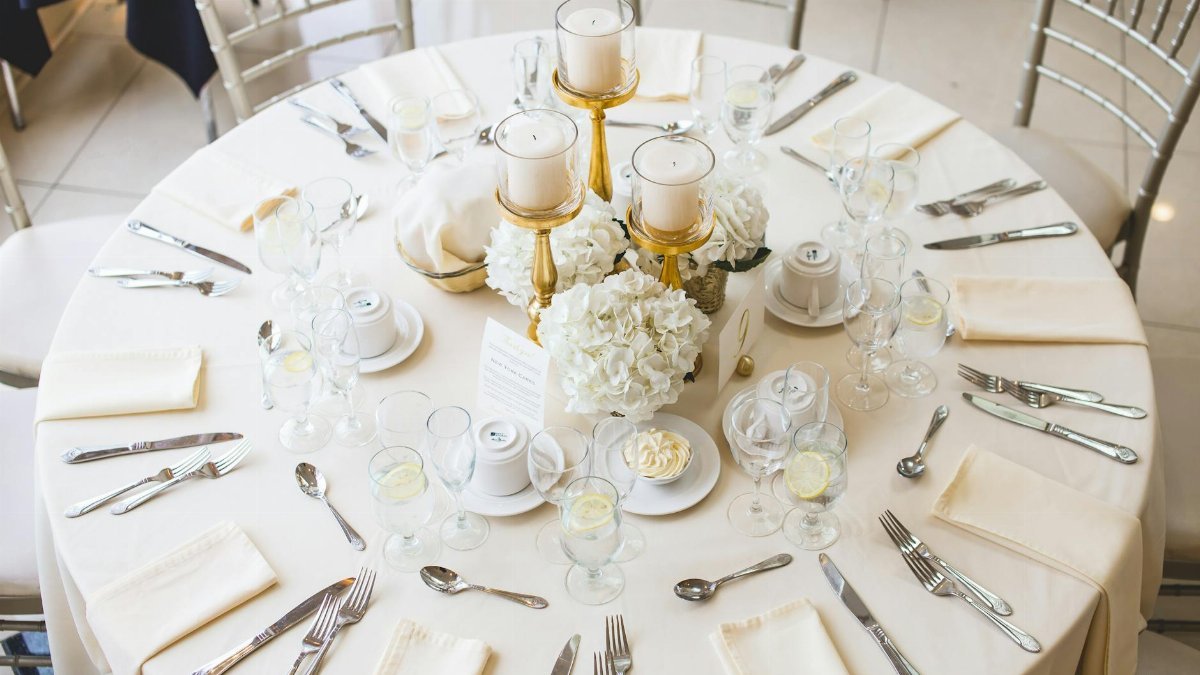 Beautifully arranged dining table setting with candles and floral centerpiece, perfect for a wedding reception.