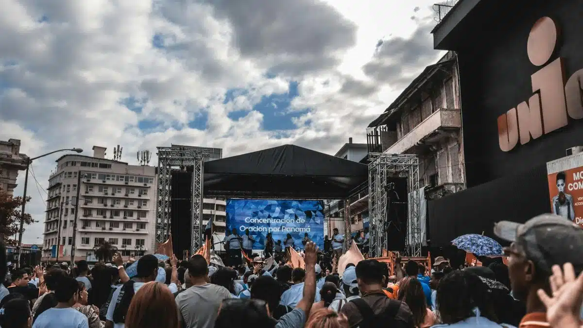 Large crowd gathered for a prayer event on an outdoor stage in the city.