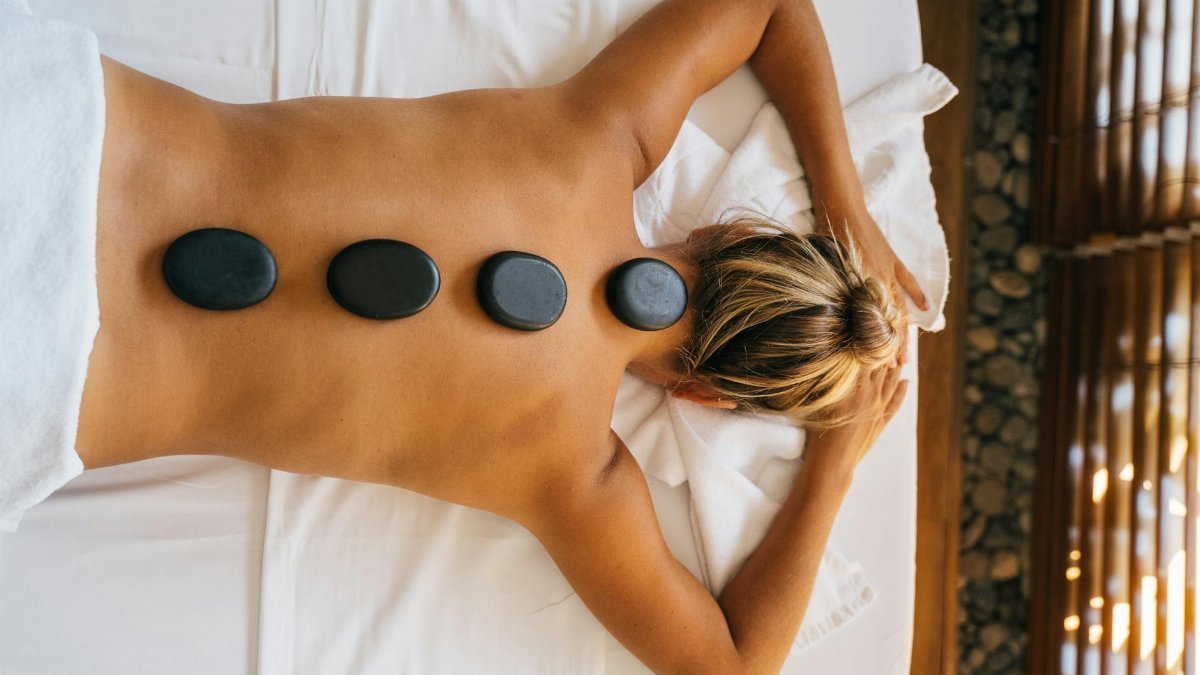 A serene hot stone massage therapy session with smooth black stones placed on the back for relaxation.