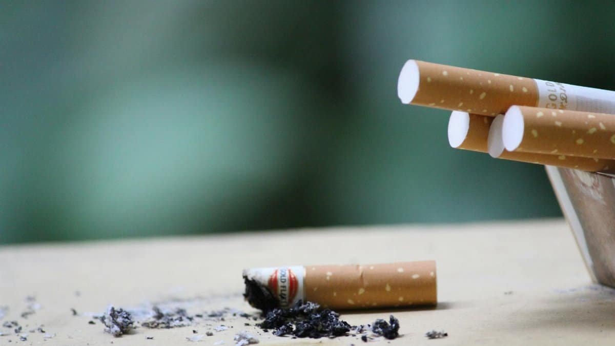 Cigarette with ashes on surface, highlighting tobacco use and health risks.