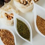 Top view of eco-friendly reusable bags with assorted grains and spices on a white surface.
