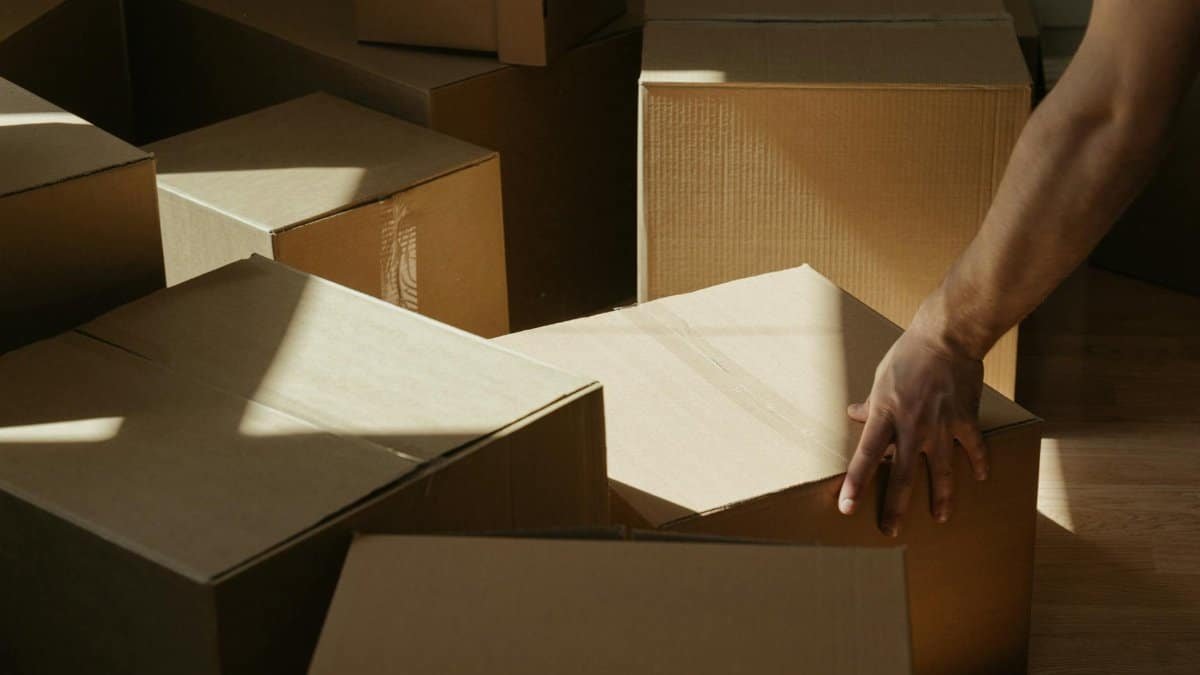 Sunlit room with person moving cardboard boxes, symbolizing relocation and new beginnings.