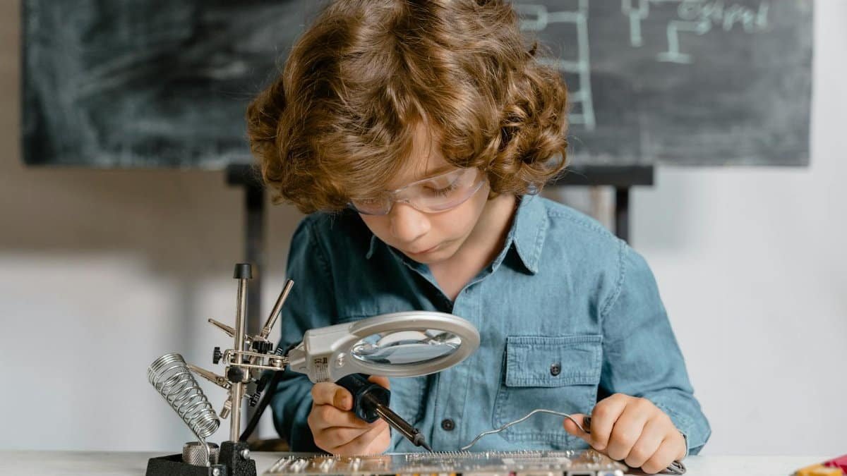 Young boy diligently working on a circuit board, exploring science and technology.
