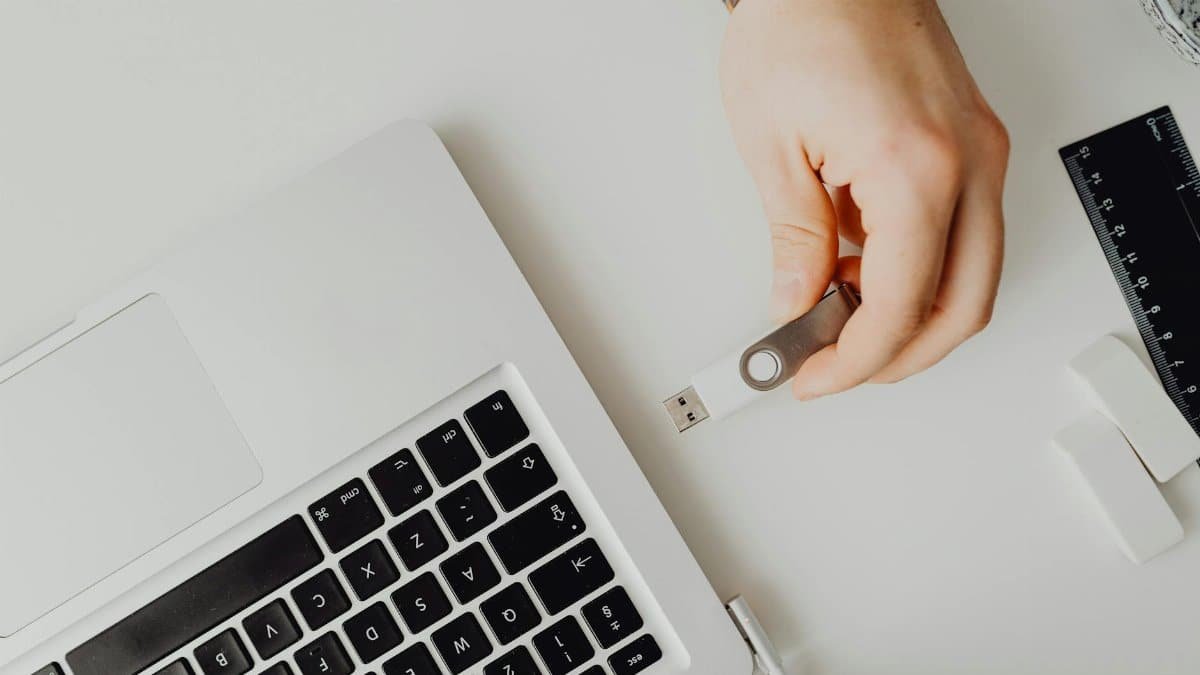 Hand inserting USB drive into laptop. Modern tech connection concept.