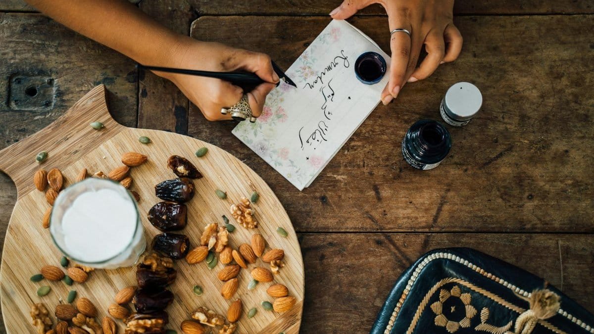 Top view of a table setting for iftar with dates, almonds, and calligraphy writing, embodying Ramadan traditions.