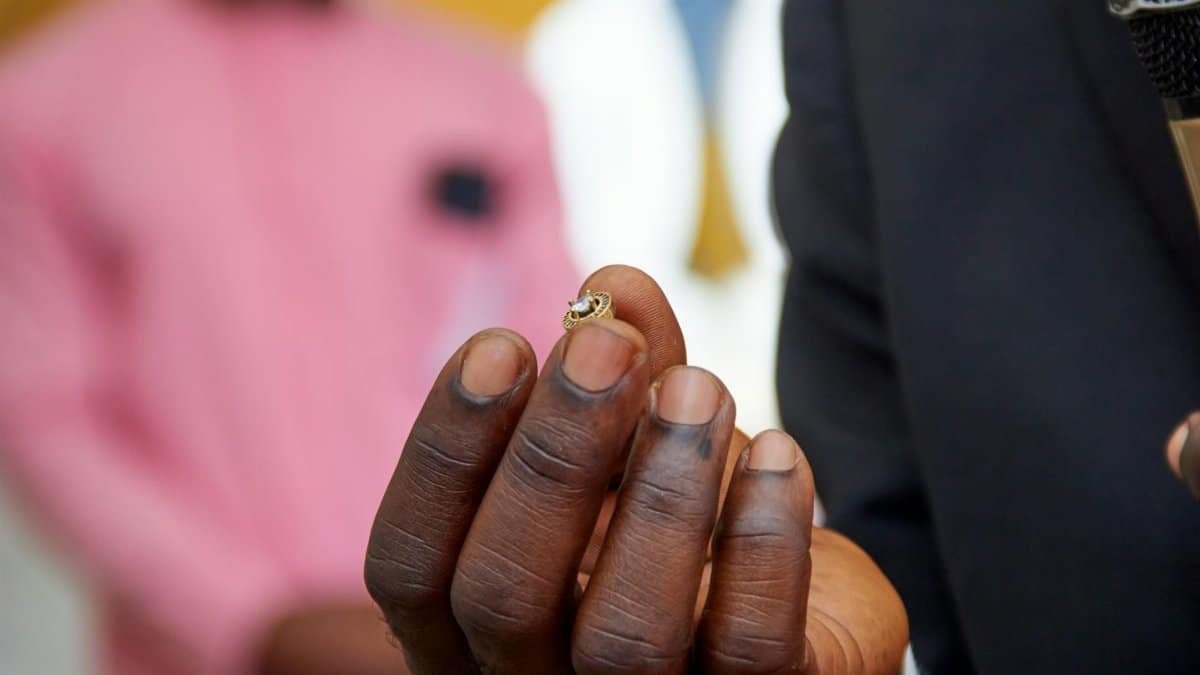 Elegant close-up of a hand holding a small ring, showcasing details and texture.