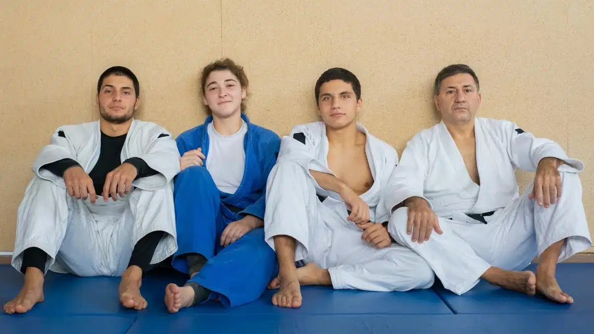 Four judo practitioners in gis sit together, showcasing teamwork and martial arts discipline.