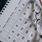 A close-up of a January calendar with eyeglasses on a table, emphasizing planning and organization.
