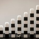 Black and white blocks steadily stacked, forming a gradual rise with a tiny zebra figurine in front.