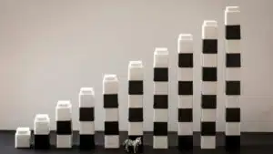 Black and white blocks steadily stacked, forming a gradual rise with a tiny zebra figurine in front.