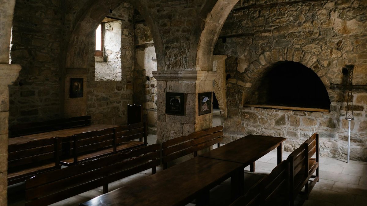 Discover the serene atmosphere of an ancient stone church with empty wooden benches and arches.