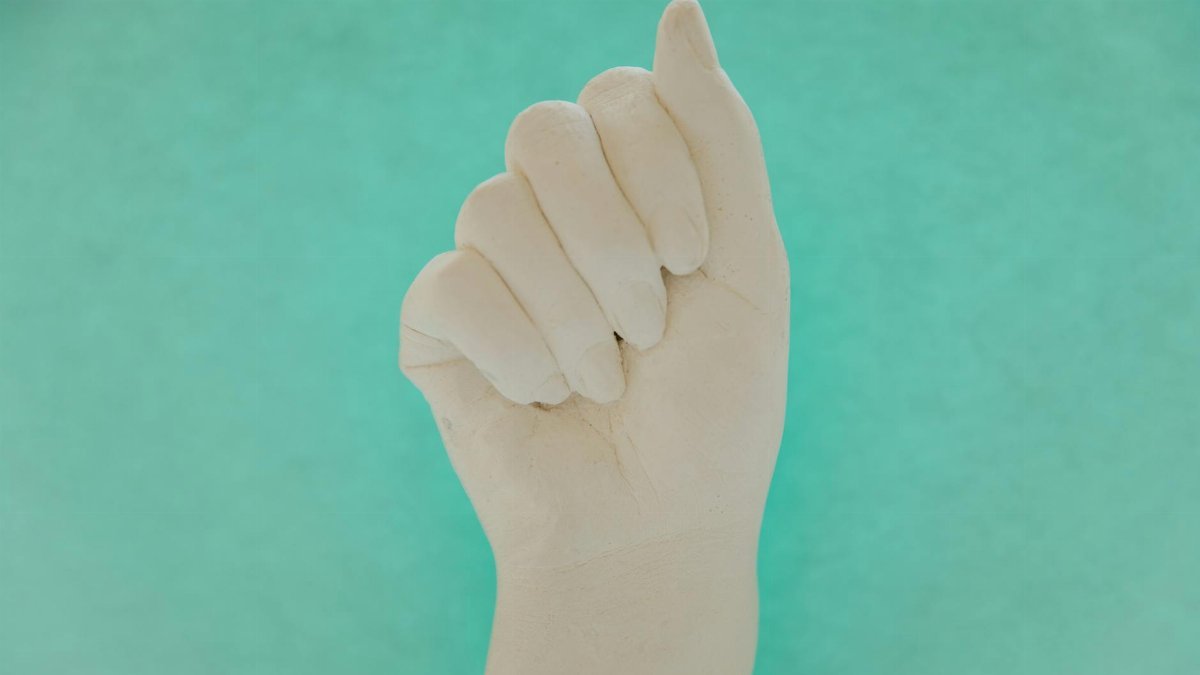 A close-up of a human hand making a fist against a blue background, offering ample copyspace.
