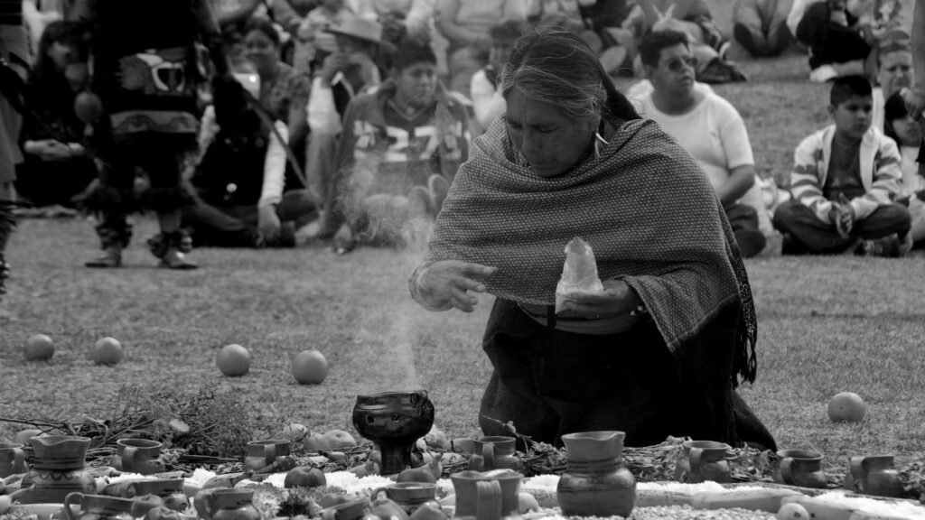 An indigenous woman performs a ritual with an audience watching closely in Mexico.