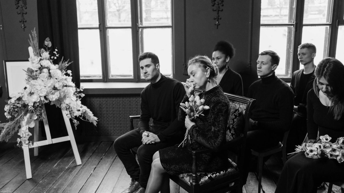 Grieving family members gather at a funeral, displaying emotions and support.