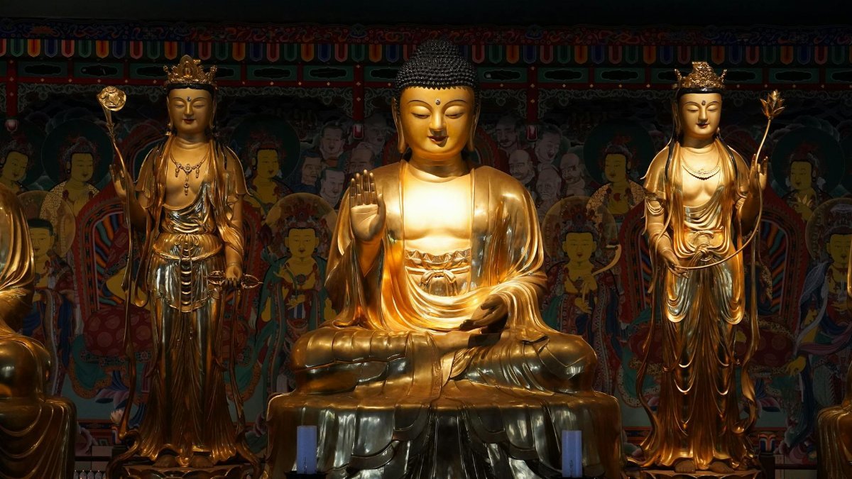 A serene arrangement of golden Buddha statues in an ornate temple ambiance.