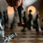 Hand placing unique chess piece on board, evoking strategy and intelligence.