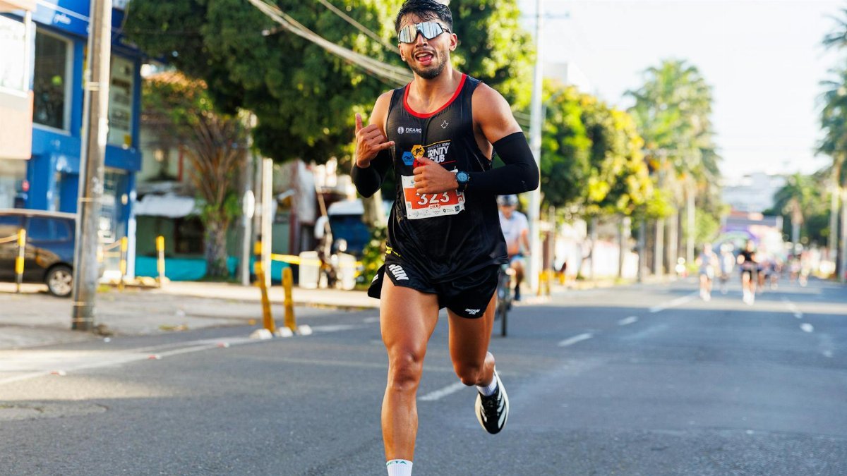 A male runner participating in an outdoor city marathon on a sunny day.