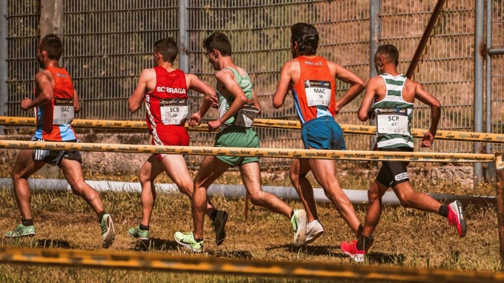 A team of male athletes competing in an outdoor cross-country race on a sunny day.