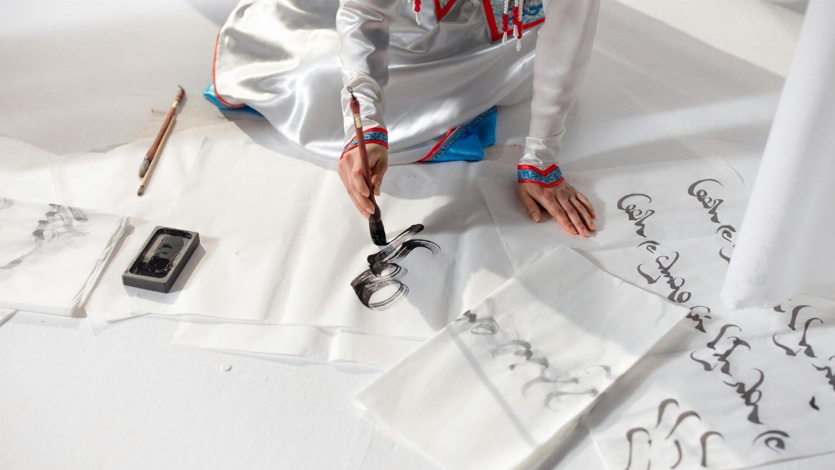 A person skillfully practicing calligraphy using traditional tools and techniques.