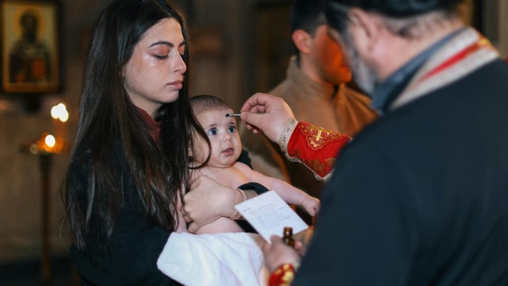 A solemn baptism ceremony with a baby and family inside a church, highlighting spiritual traditions.
