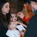 A solemn baptism ceremony with a baby and family inside a church, highlighting spiritual traditions.