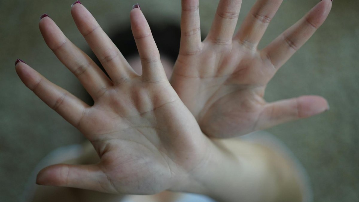 Close-up image of two hands raised with palms open in a stop gesture, emphasizing disapproval.