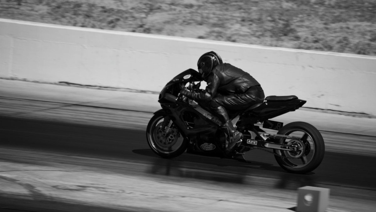 Black and white photograph capturing a motorcyclist in action during a high-speed race.