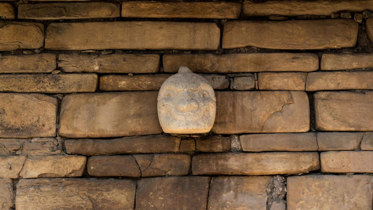 Intricate carved stone face embedded in ancient wall at Chavín de Huantar, Peru.