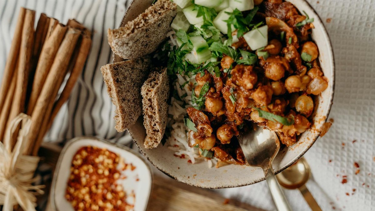 Delicious vegan bowl of chickpeas, rice, and cucumber, garnished with fresh herbs and spices.