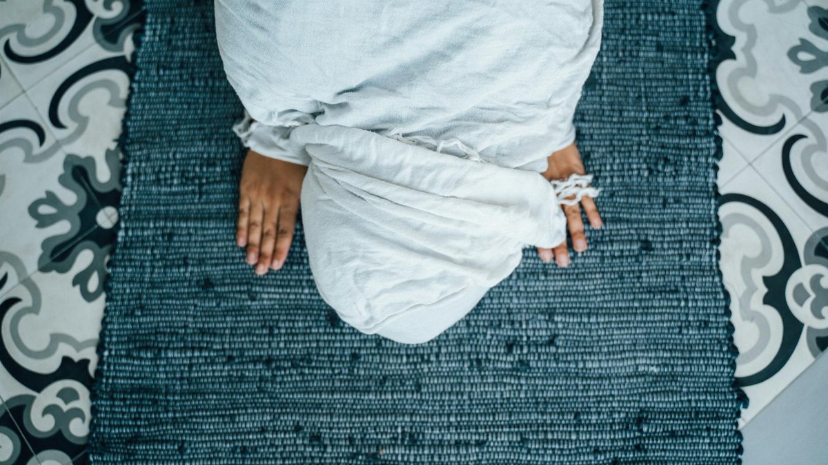Aerial shot of woman in prayer position, symbolizing faith and devotion.
