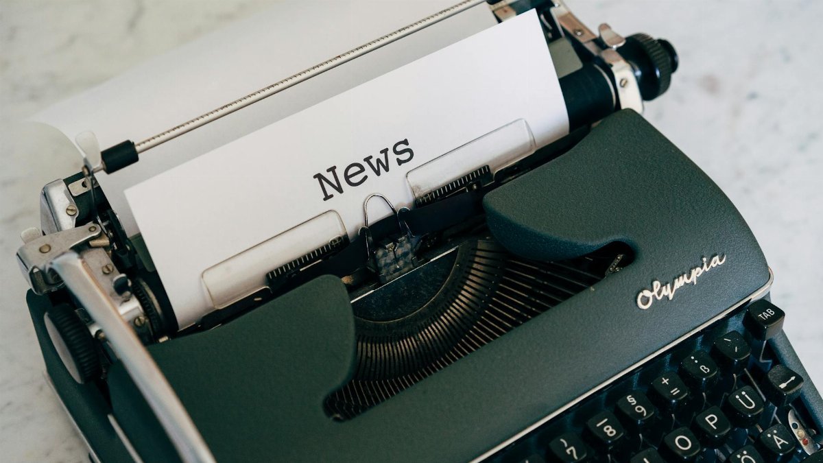Close-up of an antique typewriter with 'News' on paper.