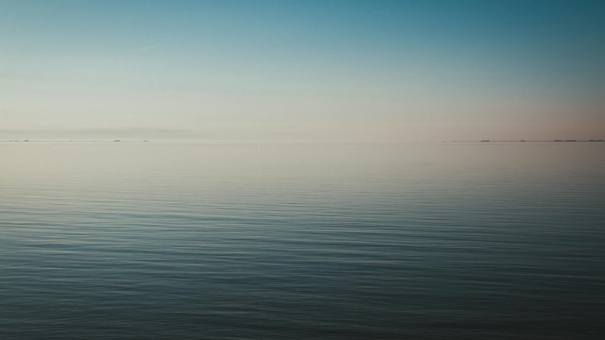 Tranquil seascape view at dawn with calm waters and a clear horizon.