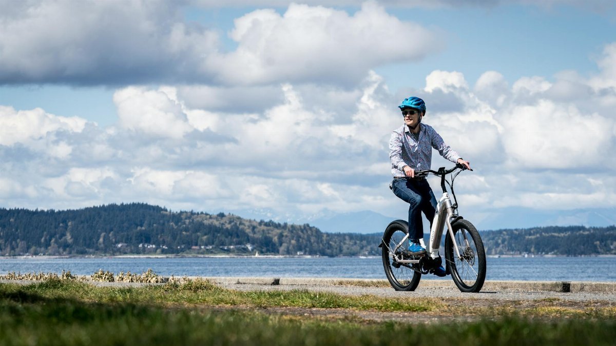 Person riding an electric bike along the Seattle waterfront on a sunny day with scenic views.