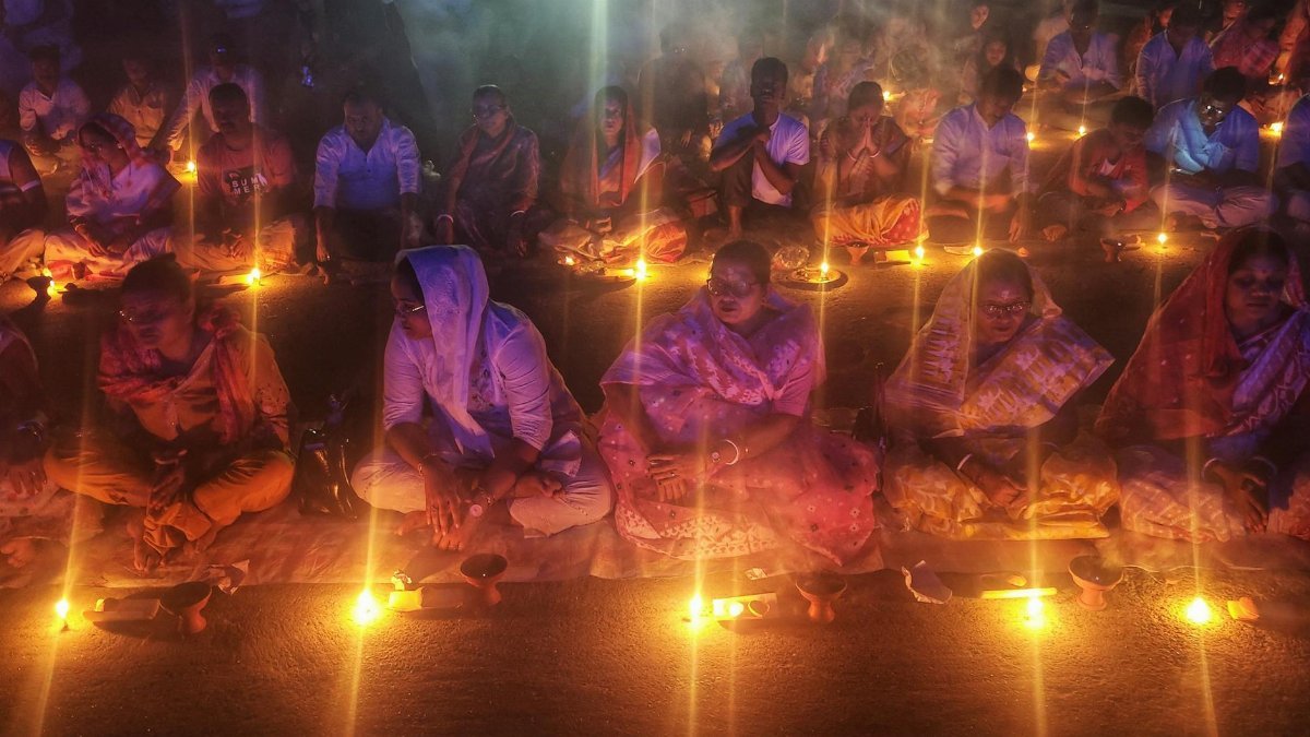 Evening candlelight prayer ritual with devotees in Kachua, West Bengal, highlighting cultural traditions.