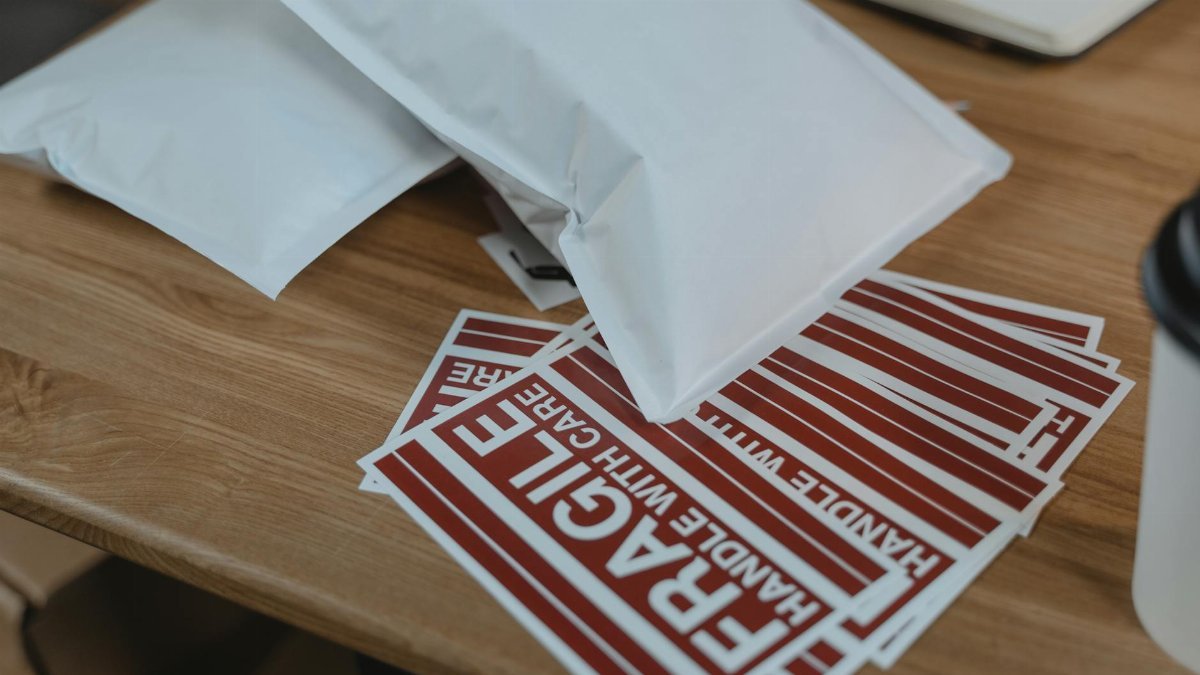 Close-up view of mailing supplies with fragile stickers on a wooden table.