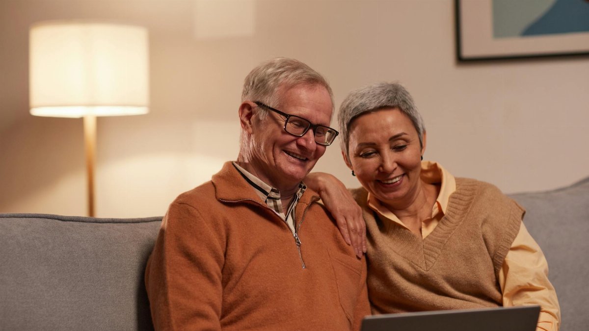Senior couple enjoying time together on laptop indoors, smiling and relaxed.