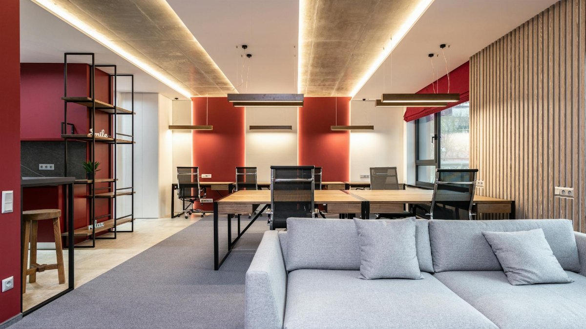 Spacious modern office featuring red accent walls, stylish furniture, and ample natural light.