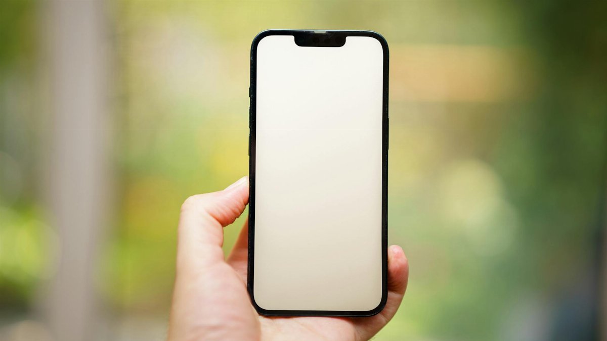 A hand holding a blank smartphone screen outdoors, ideal for mockups.