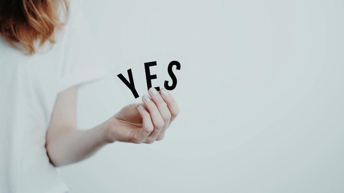 Close-up of a hand holding cards with the word 'YES' on a white background.