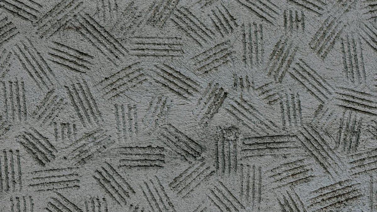 Close-up of a textured gray concrete wall with an abstract pattern of grooves.